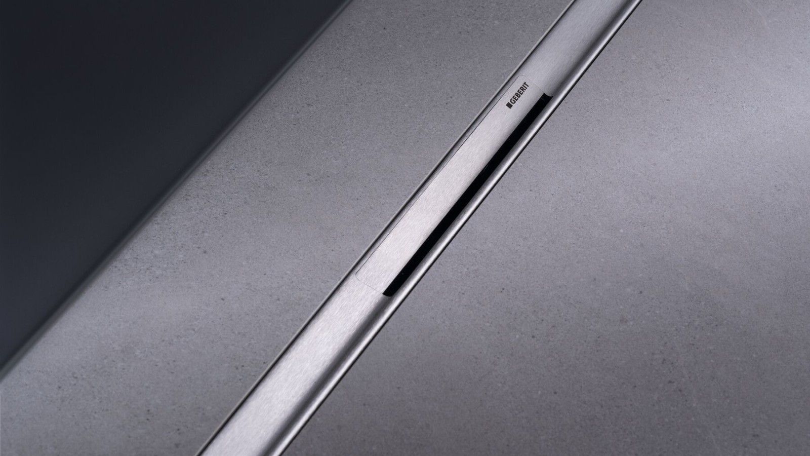 Srebrny odpływ liniowy Geberit CleanLine50 na tle ciemnych płytek Srebrny odpływ liniowy Geberit CleanLine50 na tle ciemnych płytek