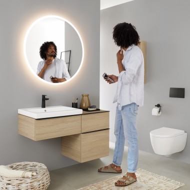 Mężczyzna patrzący na siebie w okrągłym, podświetlanym lustrze Geberit Option