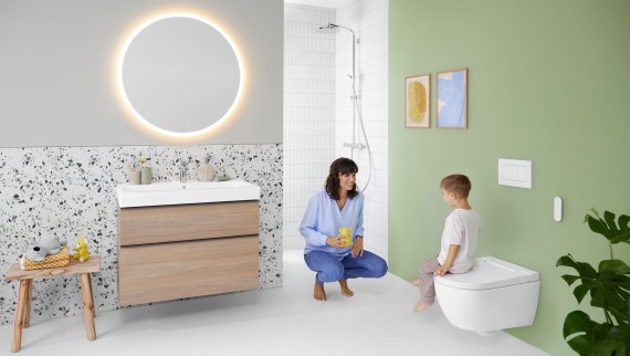 Kobieta i dziecko w kolorowej łazience z lustrem Geberit Option i toaletą myjącą Geberit AquaClean Alba Kobieta i dziecko w kolorowej łazience z lustrem Geberit Option i toaletą myjącą Geberit AquaClean Alba