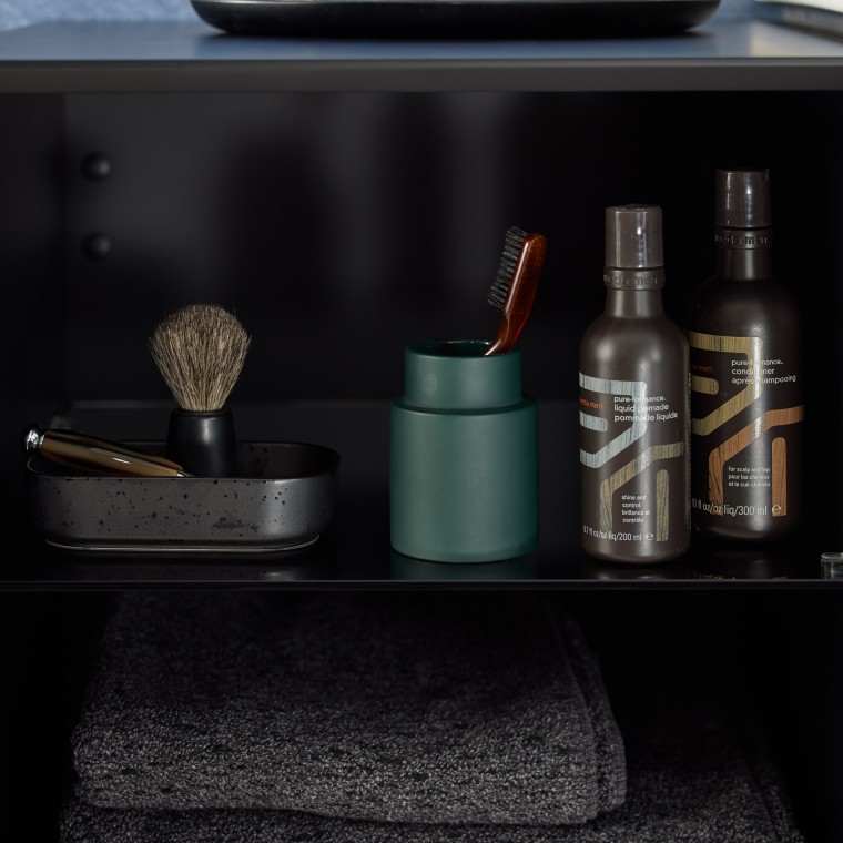 Czarna półka łazienkowa, na której znajdują się kosmetyki i przybory kosmetyczne
