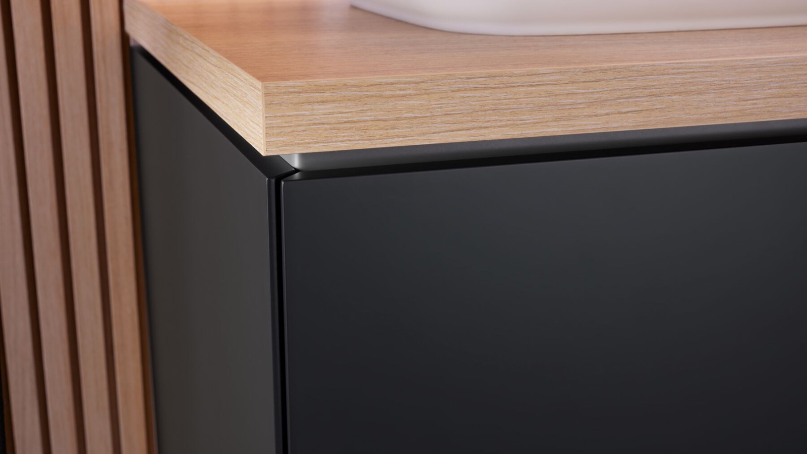 Zbliżenie na czarną szafkę łazienkową z drewnianym blatem