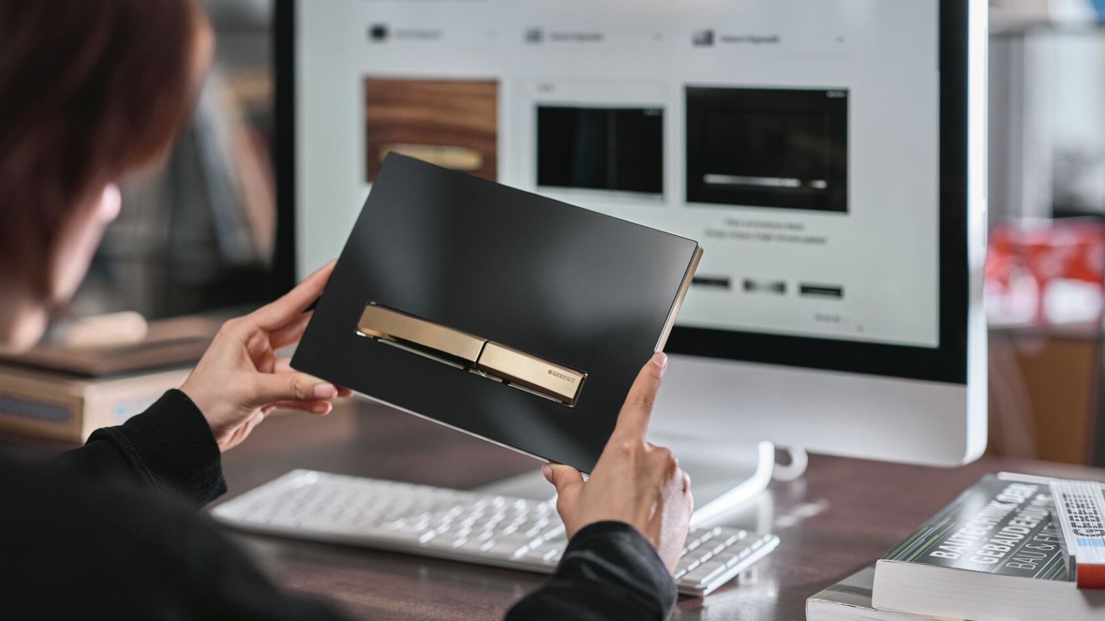 Kobieta trzyma czarny przycisk spłukujący Geberit Sigma50 z elementami z czerwonego złota