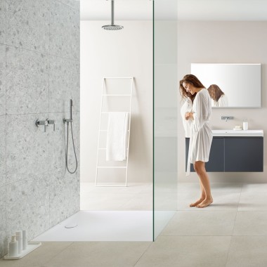 Kobieta w łazience z kabiną prysznicową walk-in i brodzikiem Geberit Olona Kobieta w łazience z kabiną prysznicową walk-in i brodzikiem Geberit Olona