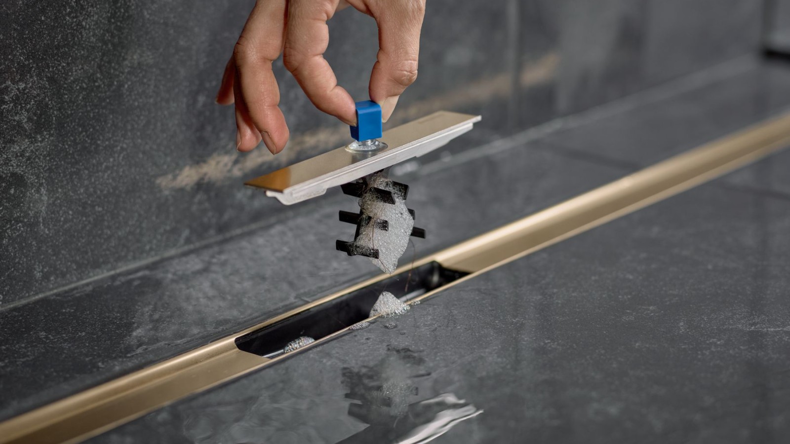 Dłoń wyjmuje wkład grzebieniowy z odpływu liniowego Geberit Dłoń wyjmuje wkład grzebieniowy z odpływu liniowego Geberit