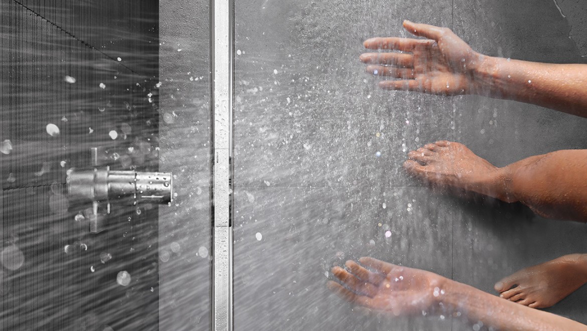 Osoba biorąca prysznic w zrównanej z podłogą kabinie natryskowej z rynną zbiorczą Geberit CleanLine