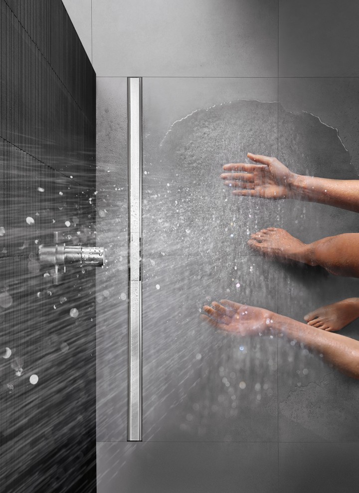 Osoba biorąca prysznic zlicowanym z podłogą, wyposażonym w odpływ liniowy Geberit CleanLine