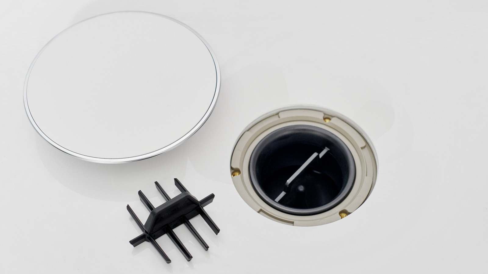 Pokrywa odpływu brodzikowego Geberit i wkład grzebieniowy leżą obok odpływu Pokrywa odpływu brodzikowego Geberit i wkład grzebieniowy leżą obok odpływu