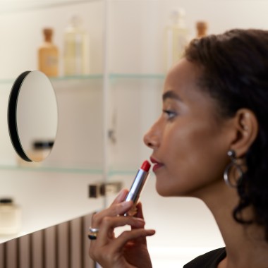 Kobieta nakładająca makijaż w lustrze
