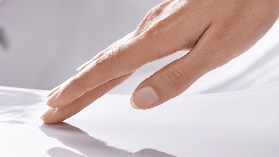 Dłoń przesuwająca się po gładkiej powierzchni ceramicznej z powłoką Geberit KeraTect