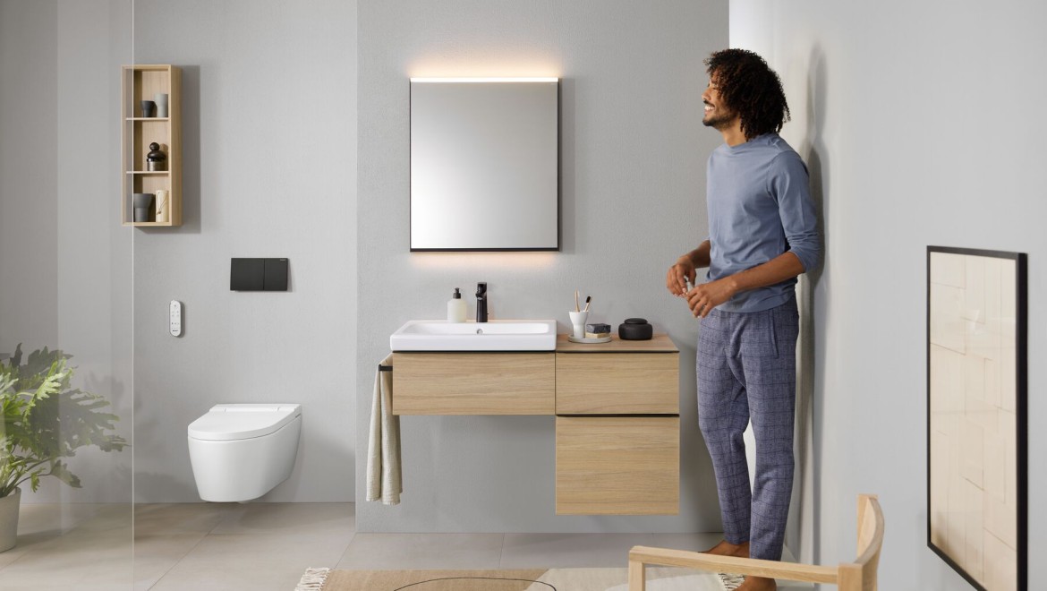 Mężczyzna stojący w łazience z toaletą myjącą AquaClean Sela