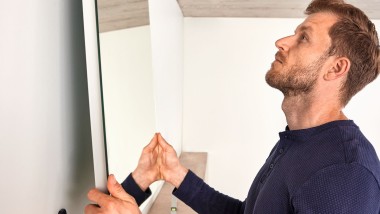 Mężczyzna wieszający lustro Geberit Option podczas remontu łazienki