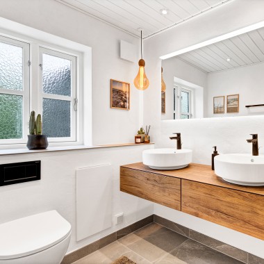 Jasna, odnowiona łazienka z dwiema okrągłymi umywalkami, dużym lustrem i drewnianymi meblami łazienkowymi (© @triner2 i @strandparken3)