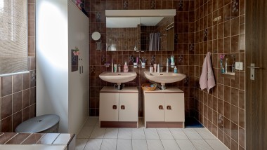 Łazienka z brązowymi płytkami i dwiema umywalkami