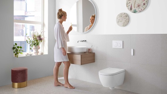 Kobieta w białej łazience z ceramiką i meblami łazienkowymi Geberit Kobieta w białej łazience z ceramiką i meblami łazienkowymi Geberit
