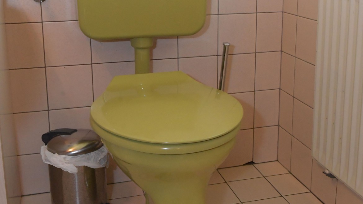 Stara toaleta z odsłoniętą spłuczką w łazience dla gości