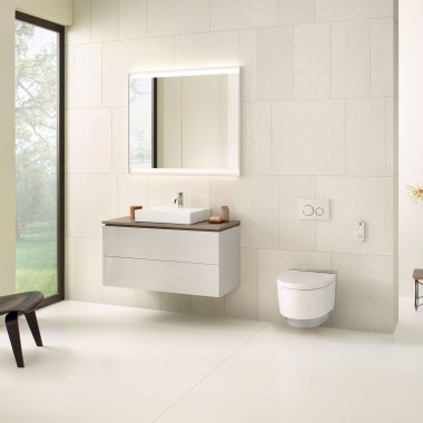 Beżowa łazienka z szafką lustrzaną, szafką pod umywalkę, przyciskiem uruchamiającym i urządzeniami ceramicznymi firmy Geberit