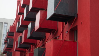 Efektowna czerwona fasada z sześciennymi balkonami od frontu przyciąga wzrok przy Goldsteinstrasse we Frankfurcie nad Menem (DE) (© Geberit)