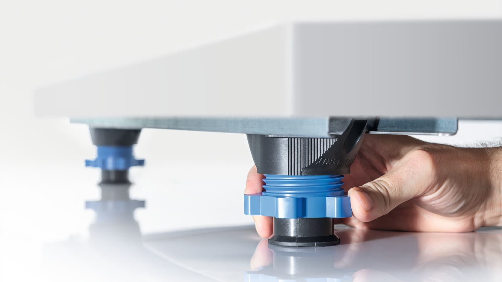 Dłoń reguluje wysokość nóżek brodzika lub panelu prysznicowego Dłoń reguluje wysokość nóżek brodzika lub panelu prysznicowego