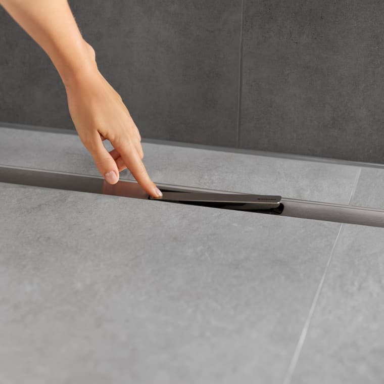 Dłoń trzymająca wkład grzebieniowy nad odpływem liniowym prysznicowym Geberit CleanLine Dłoń trzymająca wkład grzebieniowy nad odpływem liniowym prysznicowym Geberit CleanLine