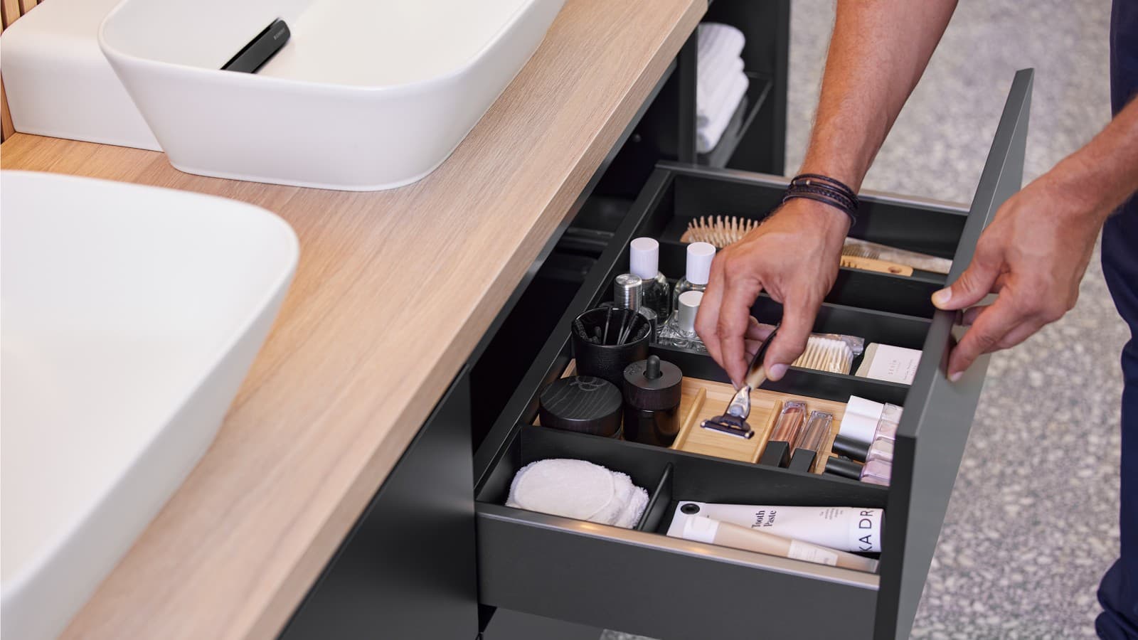 Ręka otwiera jedną z szuflad szafki podumywalkowej z serii Geberit ONE Ręka otwiera jedną z szuflad szafki podumywalkowej z serii Geberit ONE